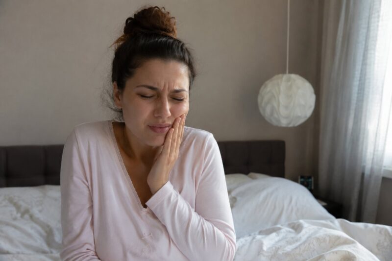 Woman holding her cheek due to severe tooth pain.