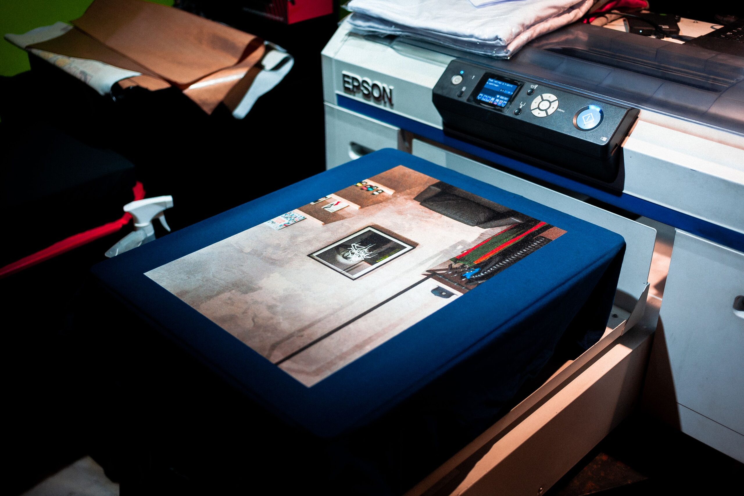Close-up of a printer applying a custom design to fabric in a small printing studio.
